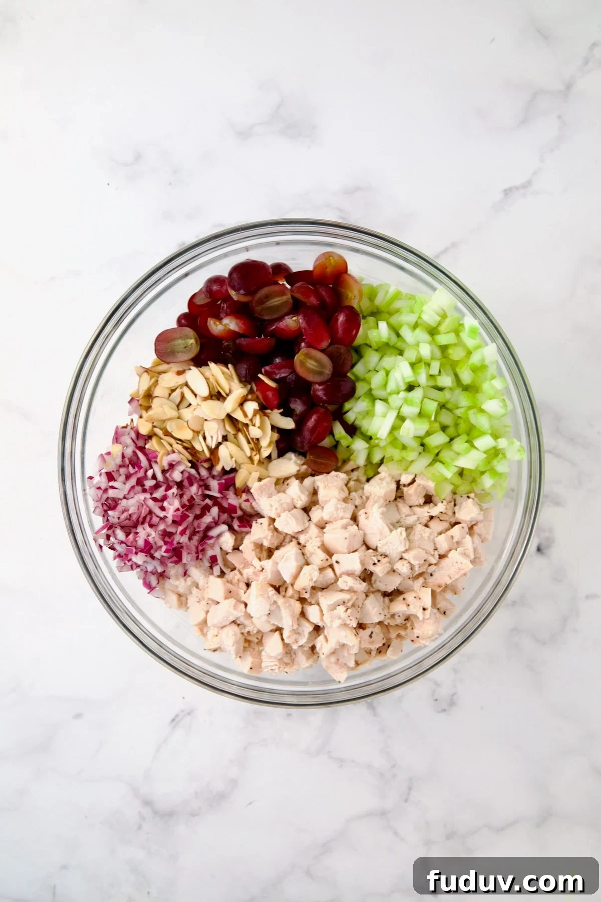 Chicken salad in glass bowl with serving spoon.