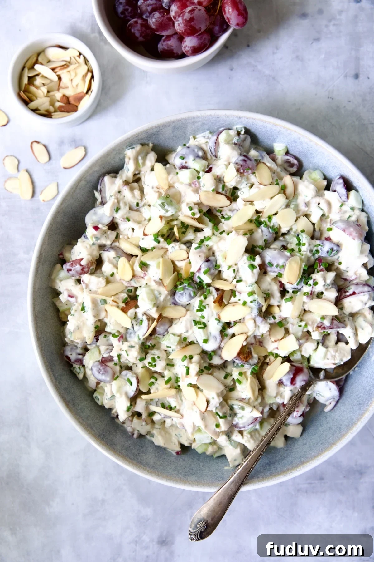 Chicken salad in blue bowl with serving spoon.