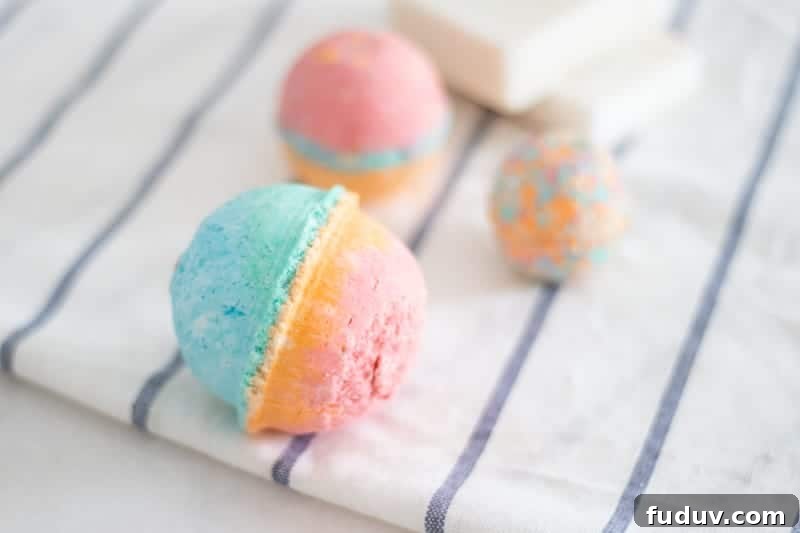 Three homemade rainbow colored bath bombs on white and blue towel.