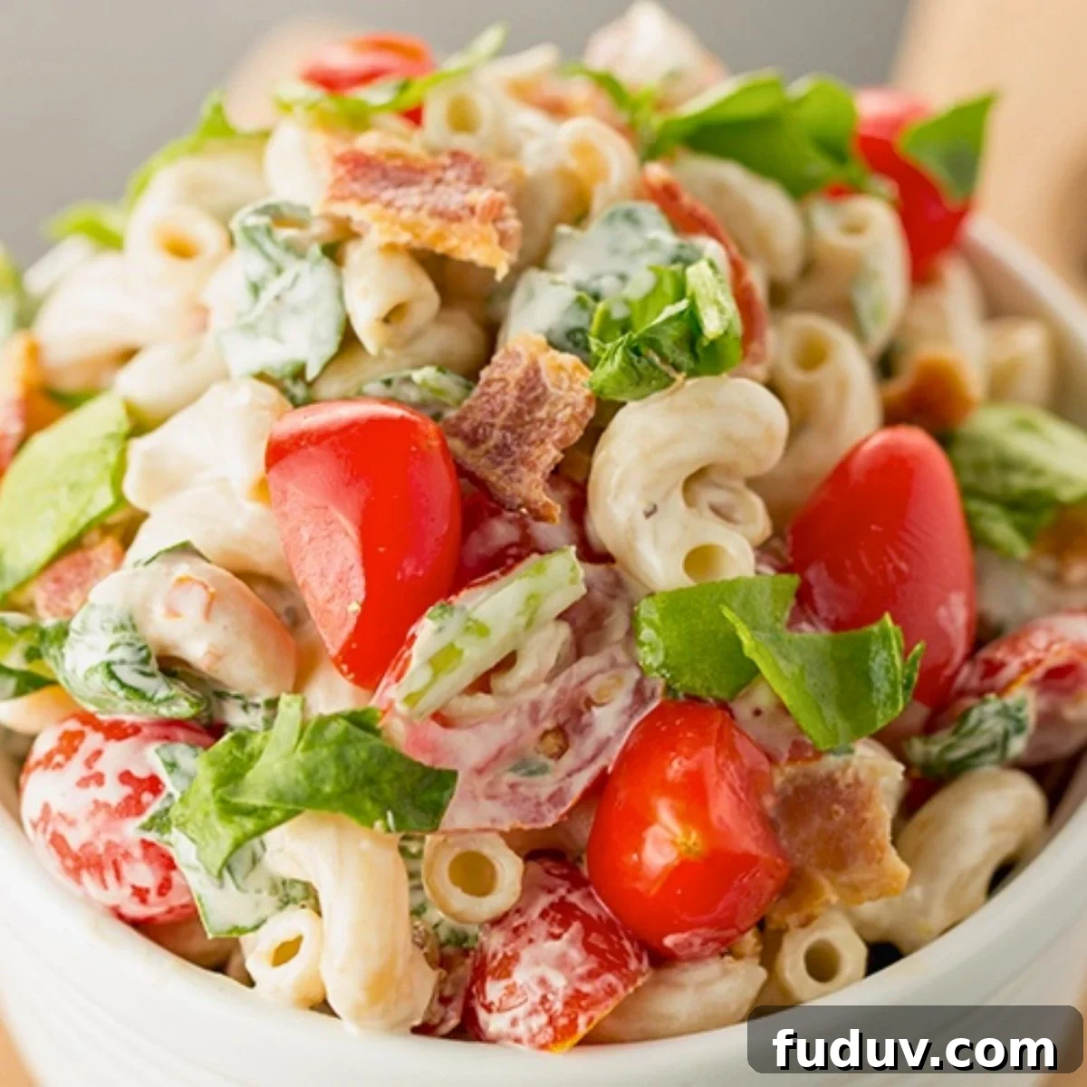 BLT pasta salad with bacon, cherry tomatoes, spinach and creamy dressing in a bowl.